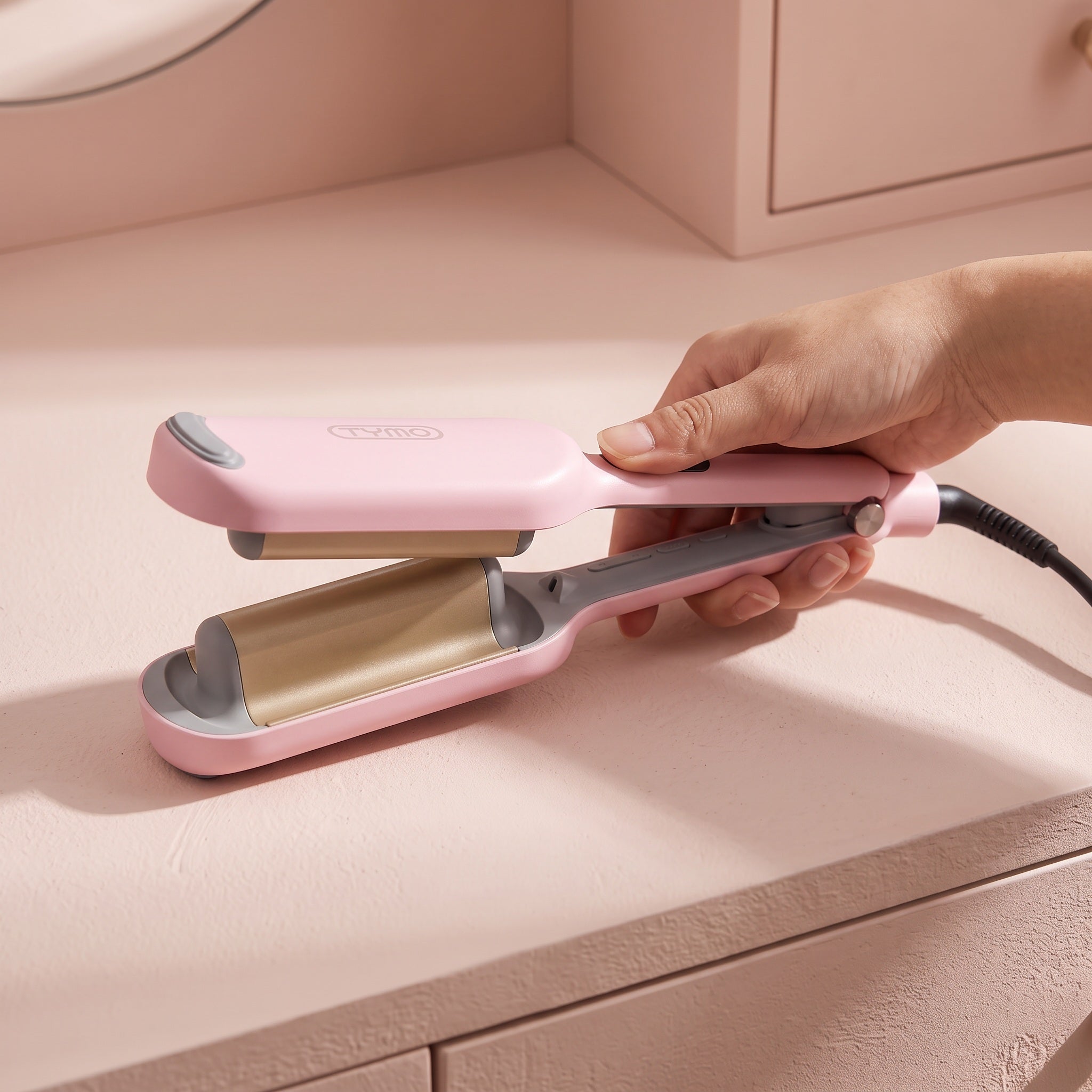 Hand opening the cooled pink waver to show its curved clamp