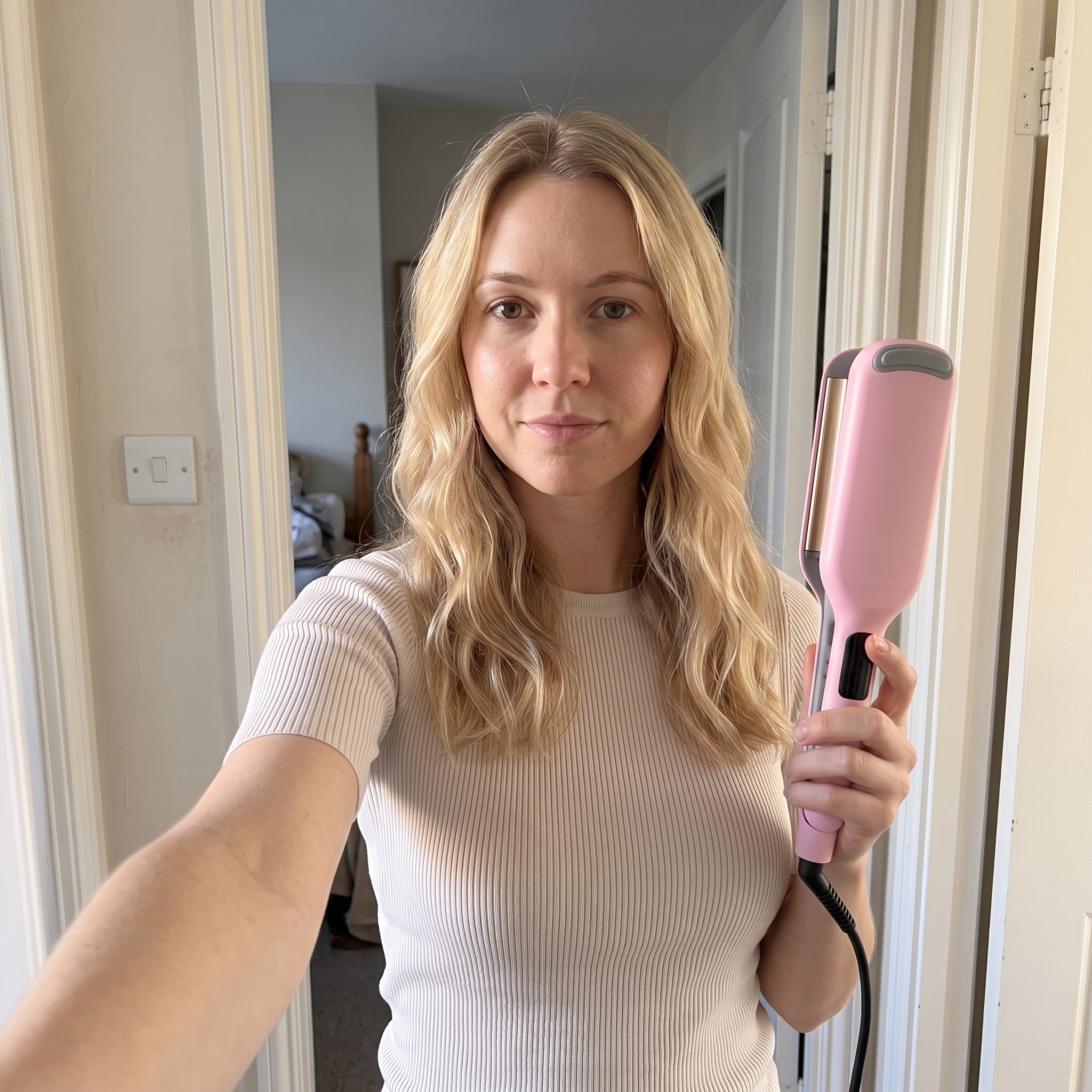 Blonde adult sharing finished waves in an arm-length front-camera selfie with the pink waver