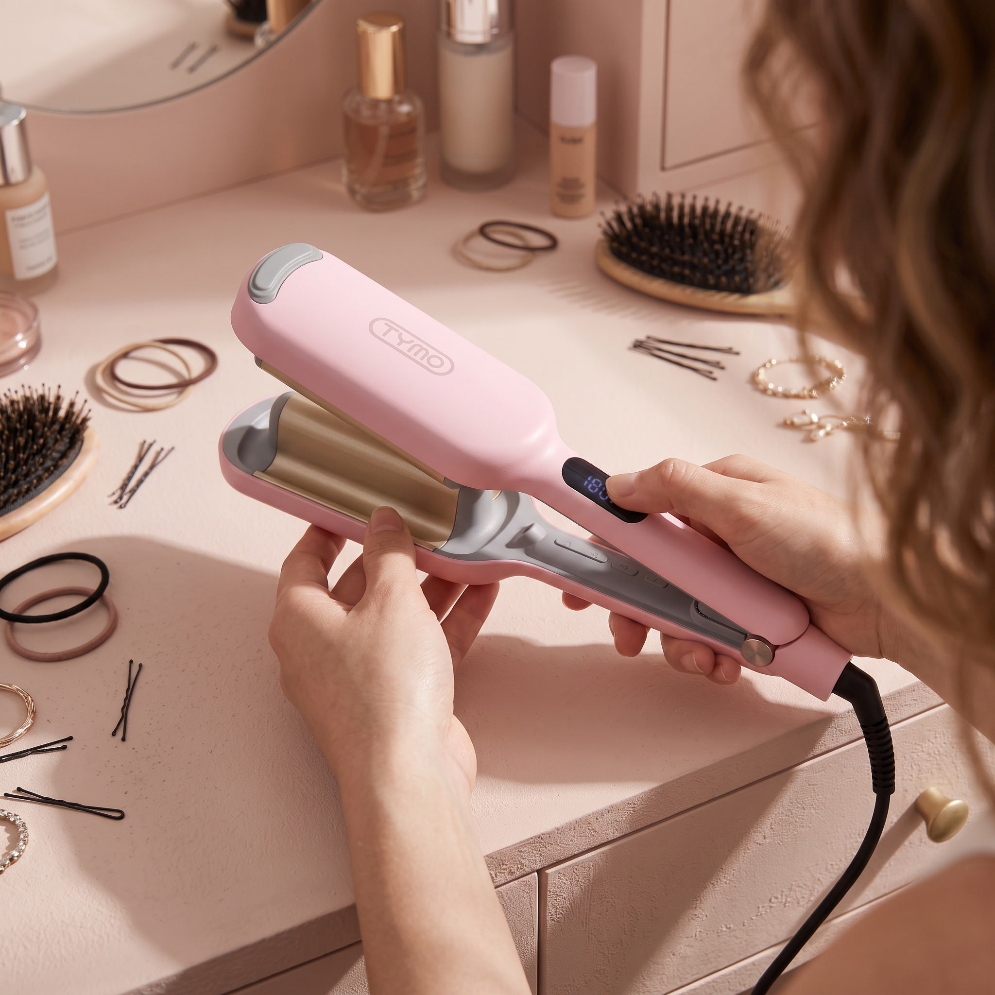 Hand choosing heat on the pink waver at a vanity
